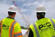 Two Primoris workers in safety vests looking at a crane